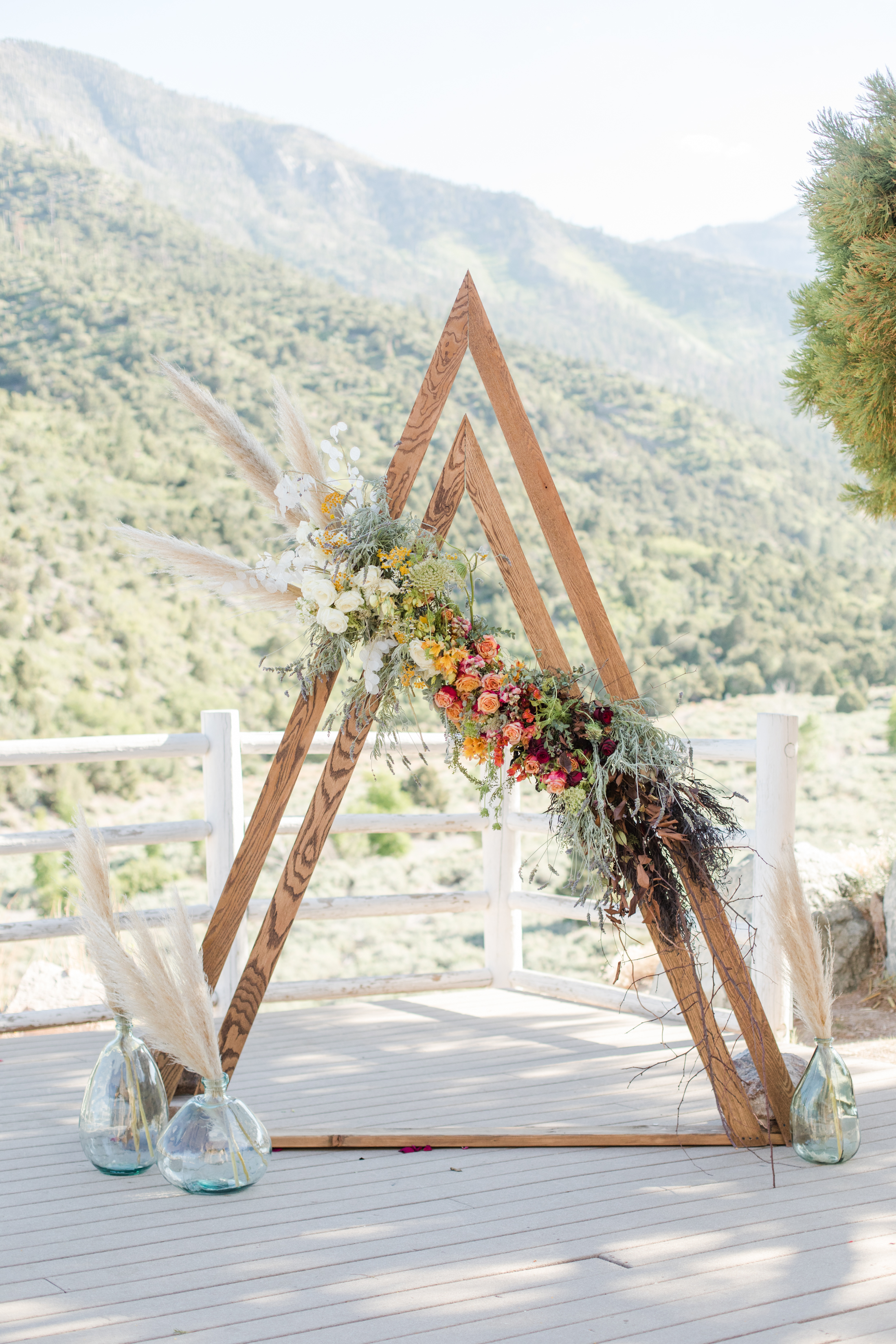 A triangle wooden ceremony arch dressed with flowers in the mountains